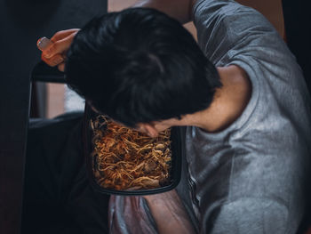 Young caucasian guy gamer eats wok food with a fork from a black container