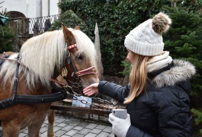 Woman touching horse during winter