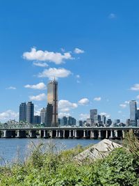 Modern buildings by river against sky in city