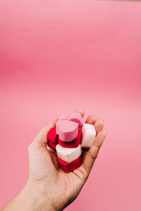 Close-up of hand holding pink over white background