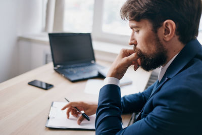 Young man using mobile phone while sitting on table