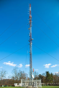 Low angle view of electricity pylon against blue sky