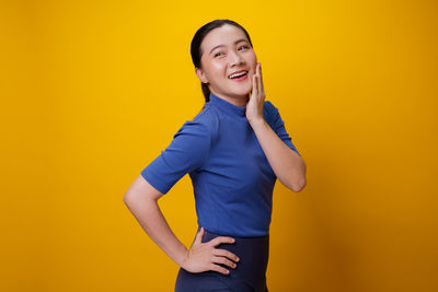 Mid adult woman standing against yellow background