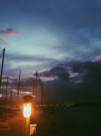 Boats in harbor against cloudy sky