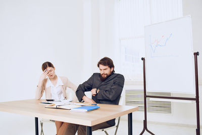 Young couple sitting on table against wall