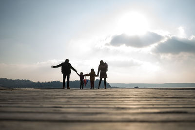 Silhouette people on beach against sky