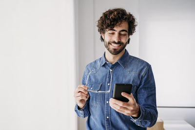 Smiling young entrepreneur using mobile phone in office