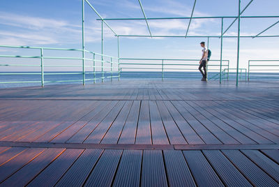 Full length of man standing by railing against sea