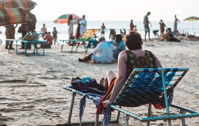 Rear view of people sitting on chair at beach