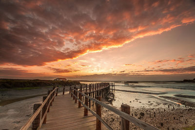 Pier over sea against sky during sunset