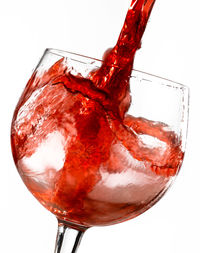 Close-up of red wine in glass against white background