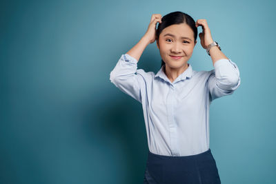 Portrait of smiling young woman against blue background