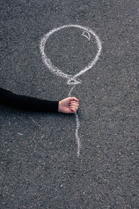 Optical illusion of hand holding balloon drawing on road