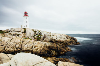 Lighthouse by sea against sky