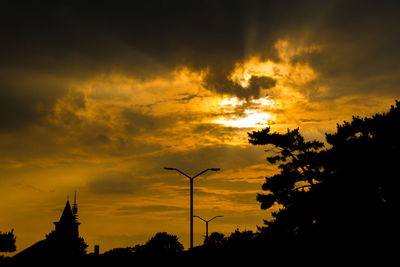 Low angle view of silhouette trees against orange sky