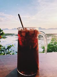 Drink in glass on table against sky