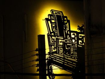 Low angle view of illuminated text on wall against building at night