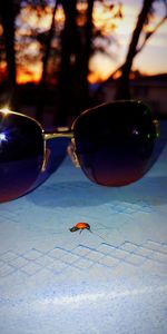 Close-up of sunglasses on land during sunset