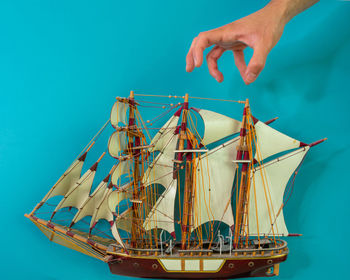 Person holding sailboat in sea against blue sky