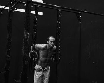 Shirtless fit young man working out in a cage at indoors gym