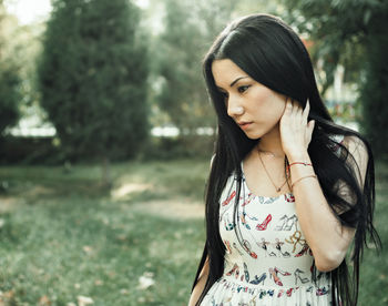 Woman looking away while standing against tree