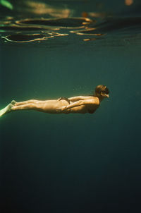 Woman free diving near nusa penida, bali, indonesia. nikonos v on 35mm cinestill 400d film.