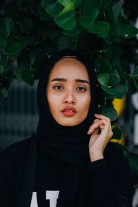 Close-up portrait of young woman in hooded shirt standing outdoors