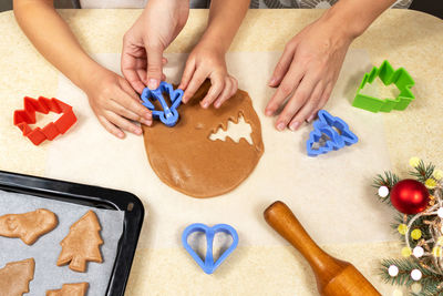 Mom and daughter with cookie cutters make christmas cookies from dough in the home kitchen. 