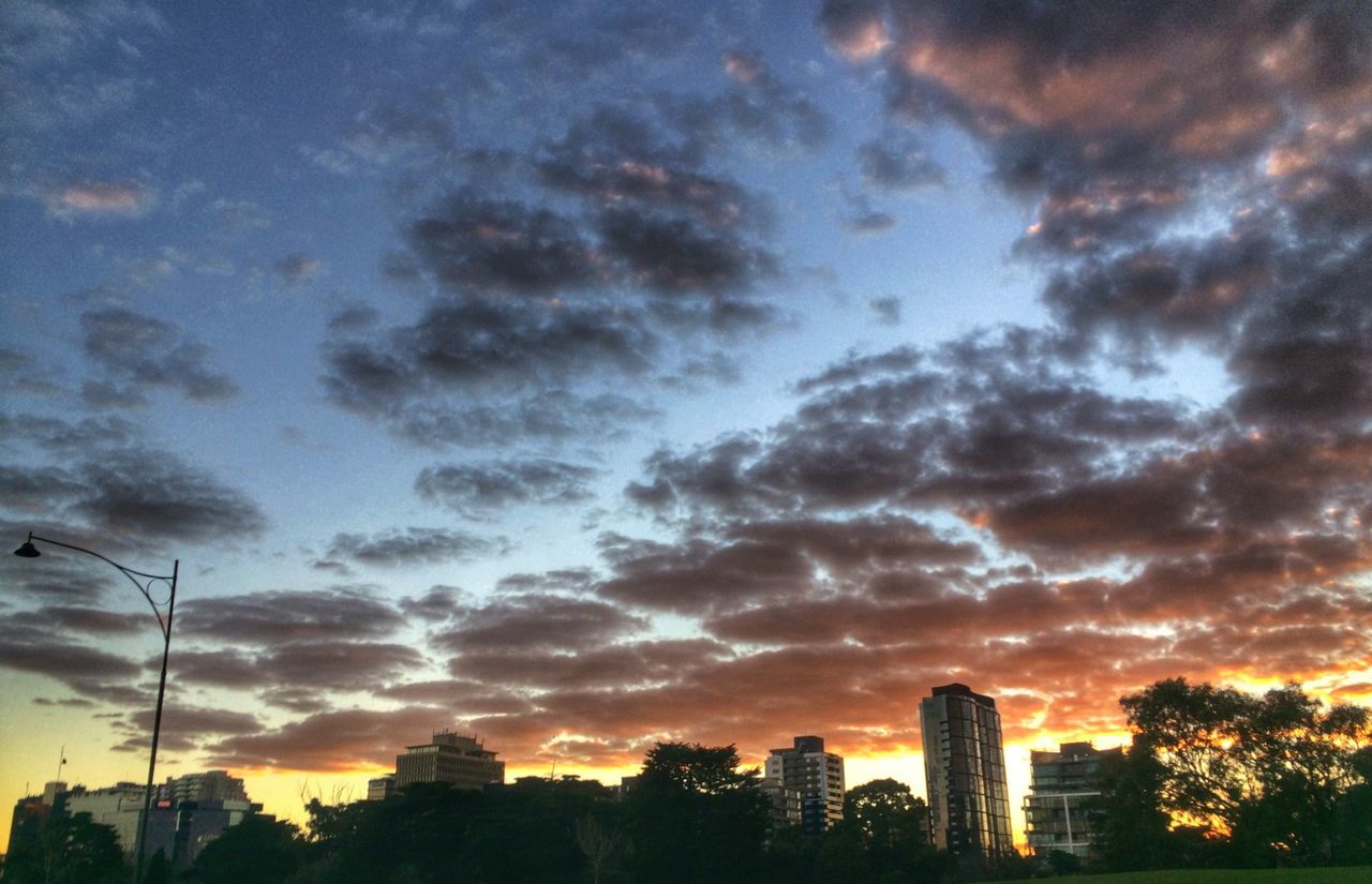 sunset, building exterior, architecture, city, sky, built structure, cloud - sky, cityscape, silhouette, skyscraper, tree, orange color, cloudy, cloud, low angle view, residential building, no people, nature, outdoors, urban skyline