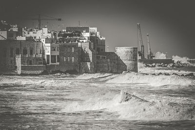 Buildings by sea against clear sky