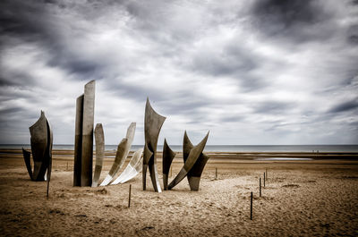 Panoramic view of wooden posts on beach against sky