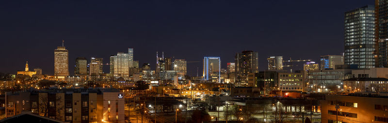 Illuminated buildings in city against sky at night