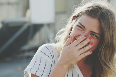 Young woman laughing while hiding mouth with hand