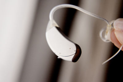 Close-up of hand holding white hearing aid