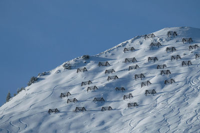 Low angle view of snow covered mountain against clear blue sky