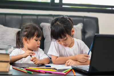 Rear view of siblings sitting on table