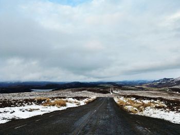 Snow covered road by mountain against sky