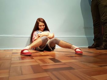 Young woman sitting on hardwood floor