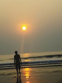 Silhouette man on beach against sky during sunset