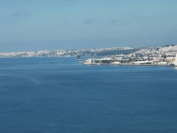 Aerial view of city by sea against sky