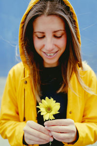 Portrait of young woman holding yellow flower