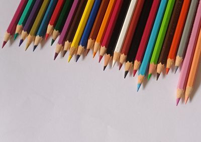 High angle view of colored pencils against white background