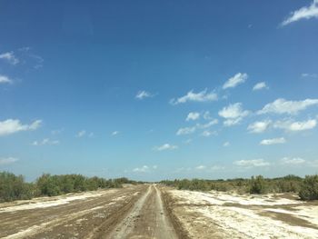 Empty road amidst landscape against sky