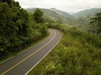 Aerial view of countryside road passing through the lush greenery tropical rain forest mountain