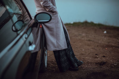 Low section of woman standing by car