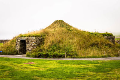 House on green landscape against sky