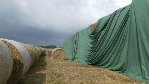 Stack of hay bales on field against sky