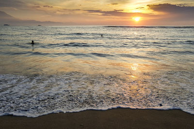 Scenic view of beach against dramatic sky during sunset