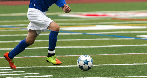 Low section of people playing soccer on field