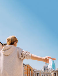 Rear view of woman standing against blue sky